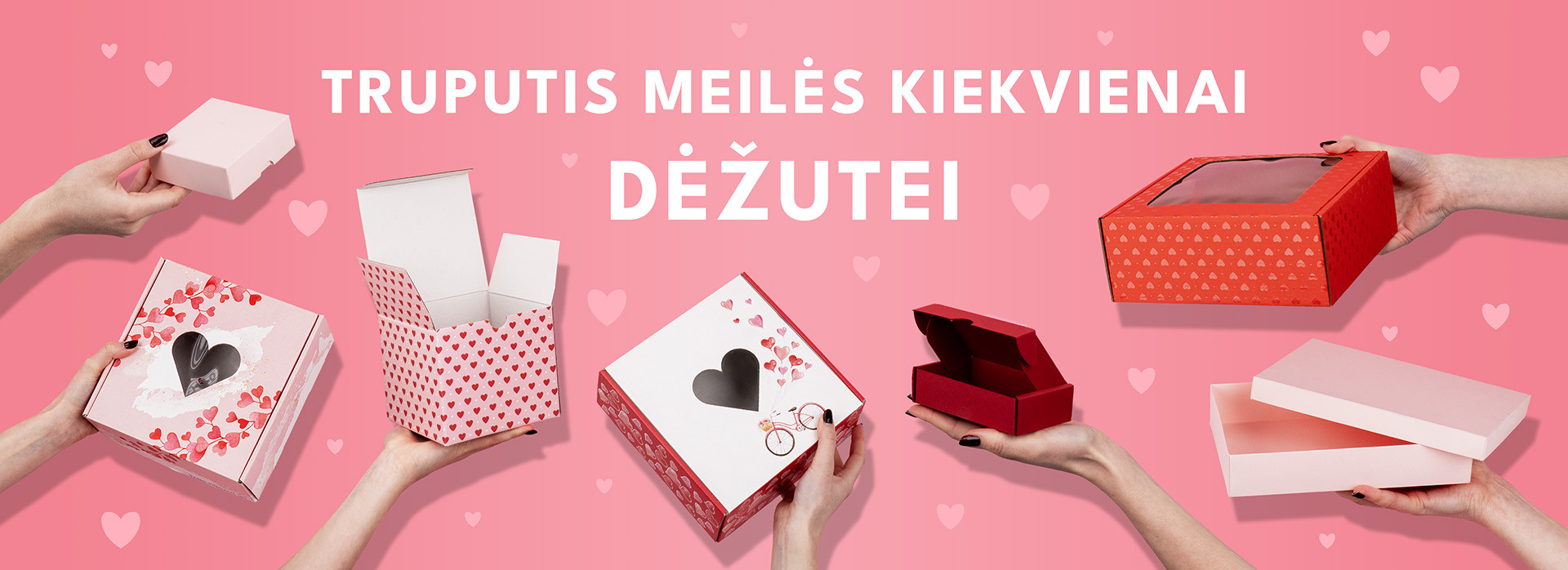 Rankose laikomos širdelėmis dekoruotos dėžutės rožiniame fone, perteikiančios žinutę „Truputis meilės kiekvienai dėžutei“.